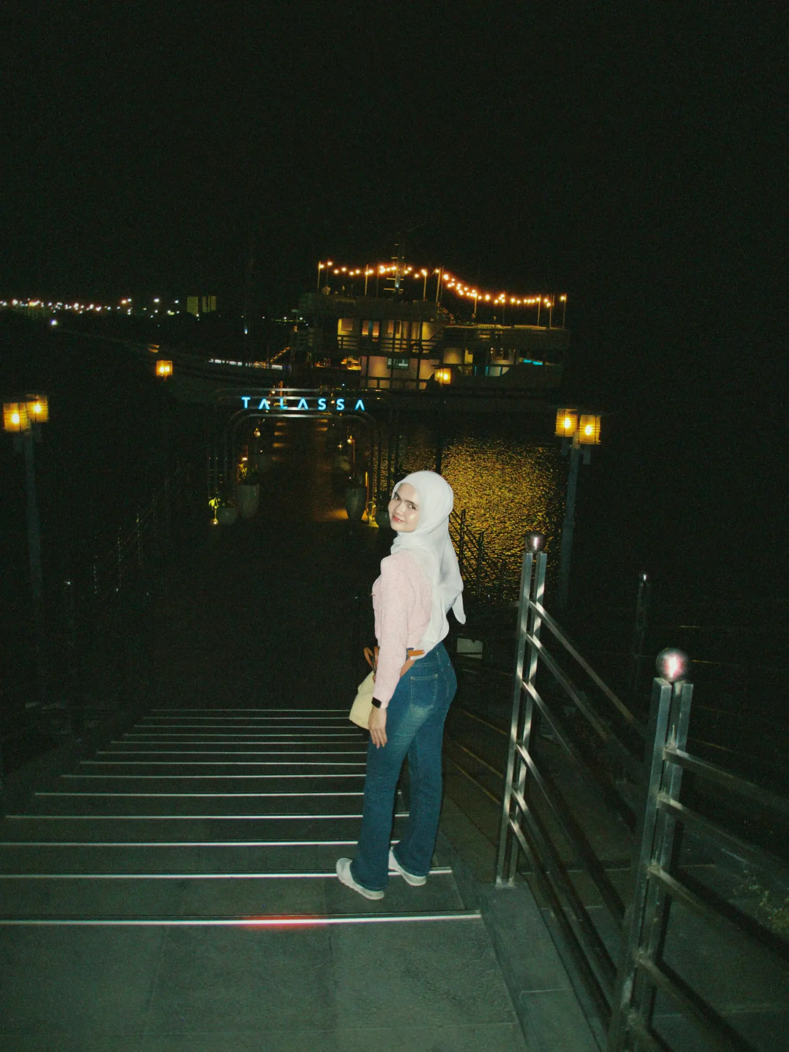 A girl on a lit boardwalk at night