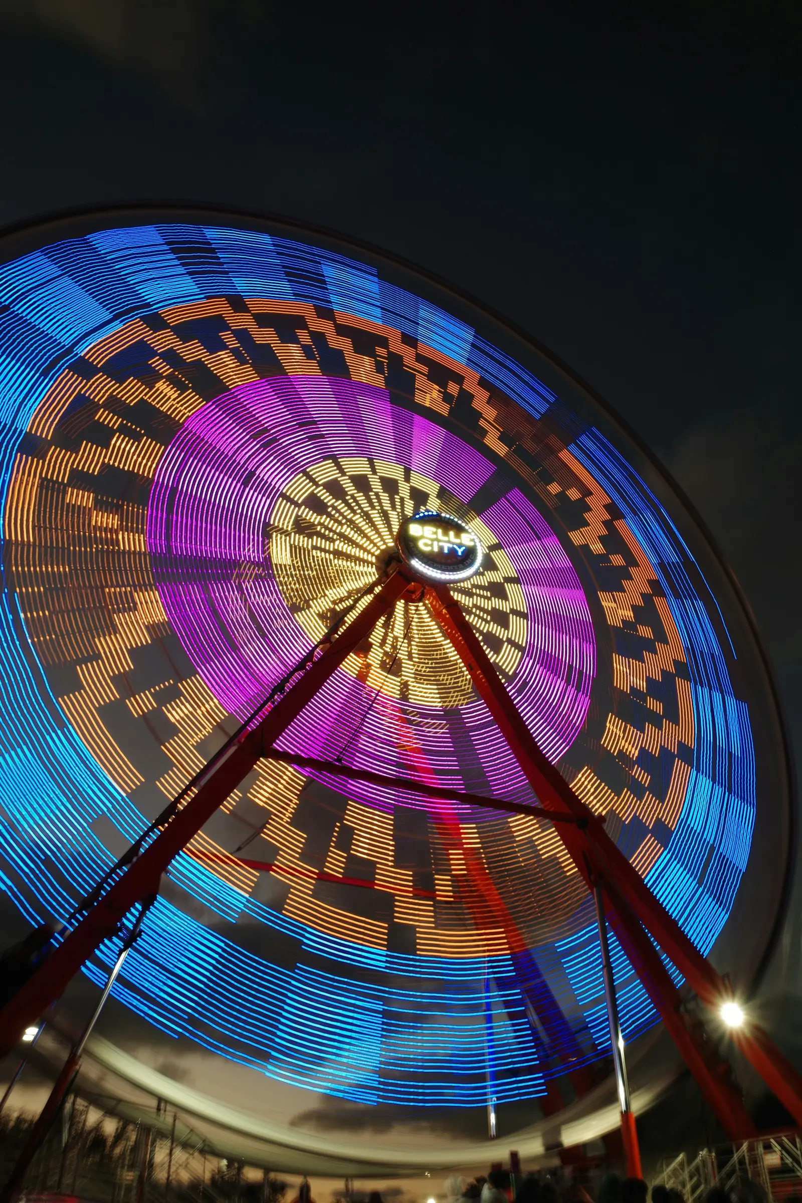 A ferris wheel spinning in neon at night