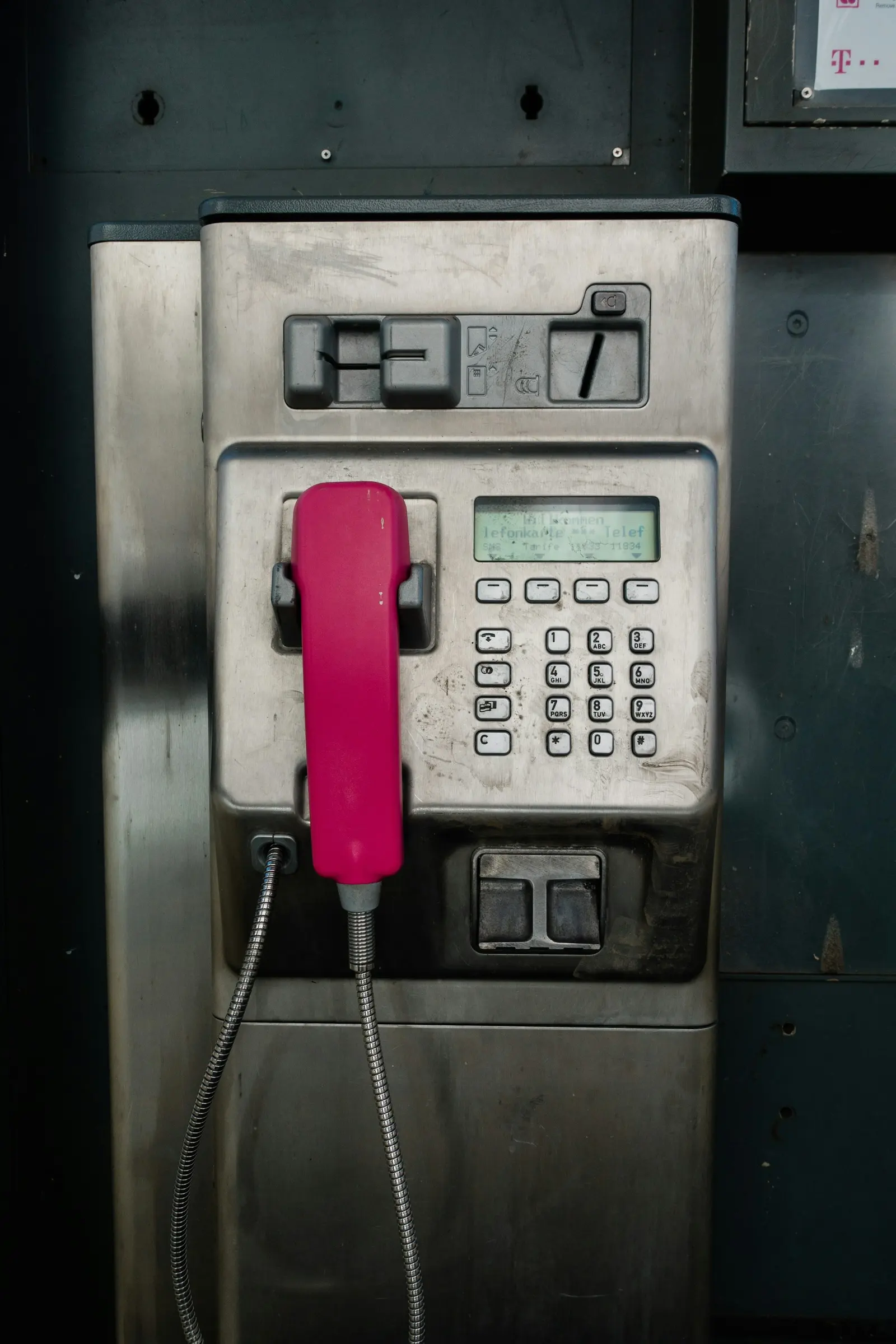 A pink payphone on a tiled wall