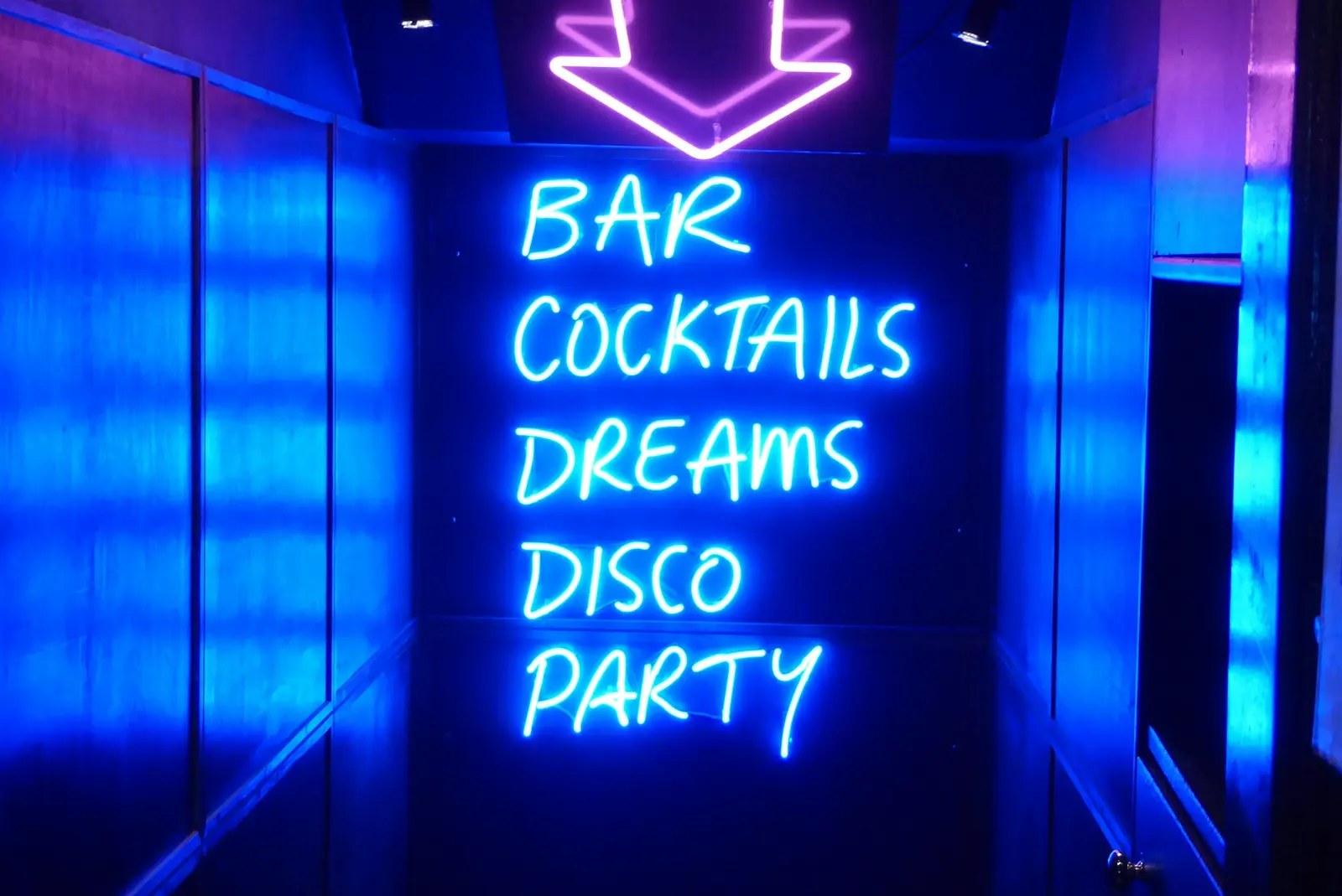 A blue neon sign: bar, cocktails, dreams, disco, party